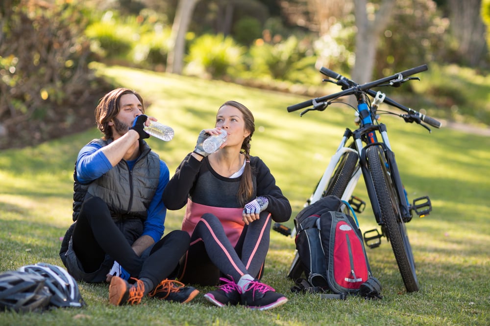 Biker couple relaxing and having water in countryside park